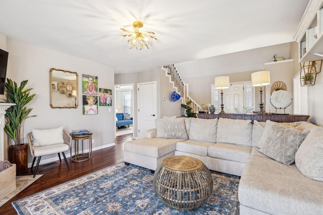 living area featuring dark wood finished floors, baseboards, and stairs