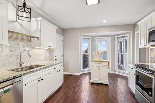 kitchen with hanging light fixtures, white cabinetry, appliances with stainless steel finishes, and a sink