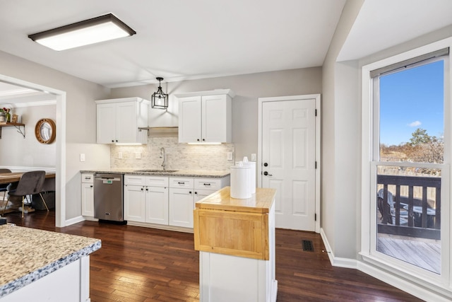 kitchen with decorative backsplash, white cabinets, a sink, and stainless steel dishwasher