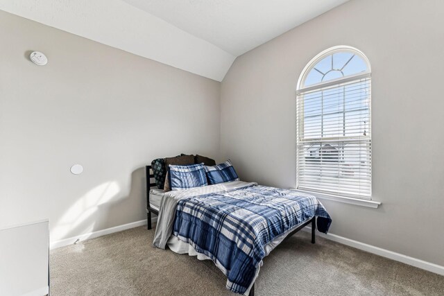 carpeted bedroom featuring baseboards and vaulted ceiling