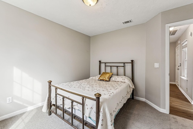 carpeted bedroom with baseboards, visible vents, and a textured ceiling