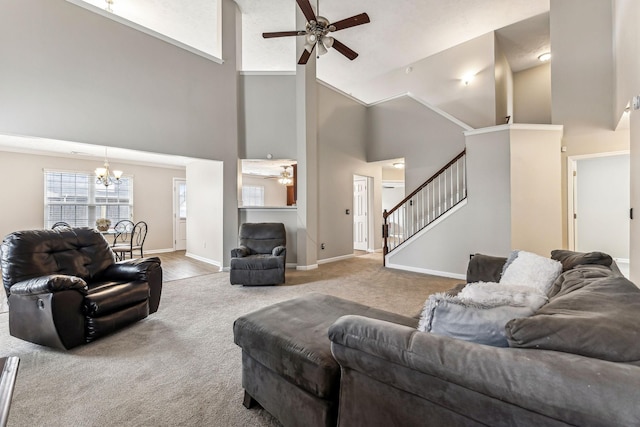 carpeted living room with ceiling fan with notable chandelier, stairway, a towering ceiling, and baseboards