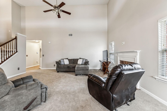 living area featuring a fireplace, carpet flooring, ceiling fan, baseboards, and stairs