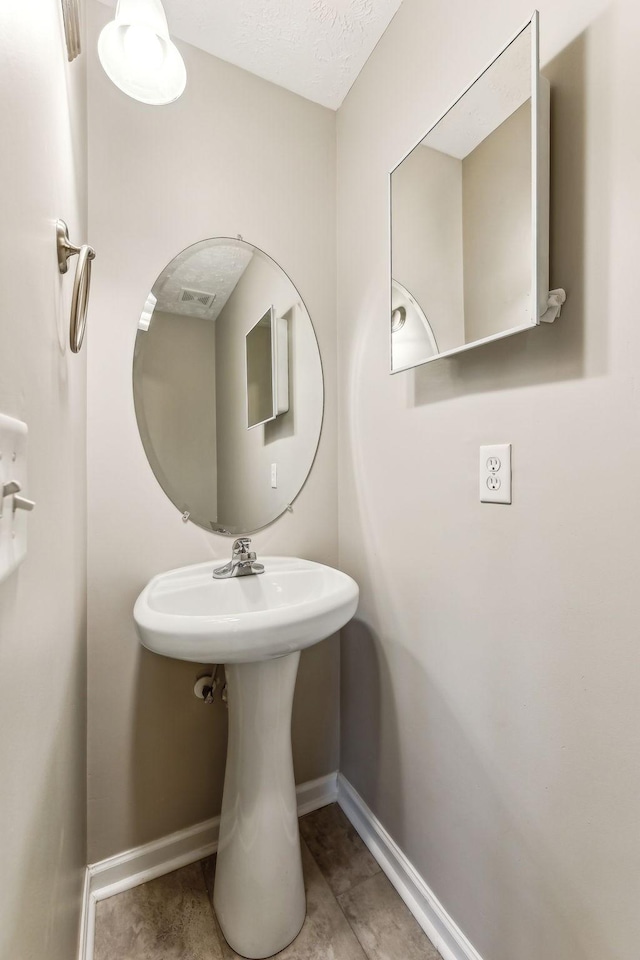 bathroom featuring tile patterned flooring, visible vents, baseboards, and a textured ceiling