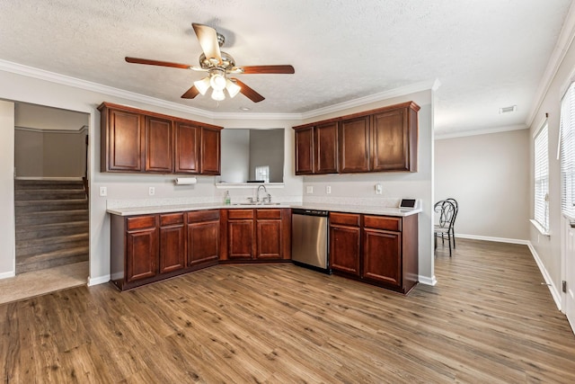 kitchen with a sink, wood finished floors, light countertops, stainless steel dishwasher, and crown molding