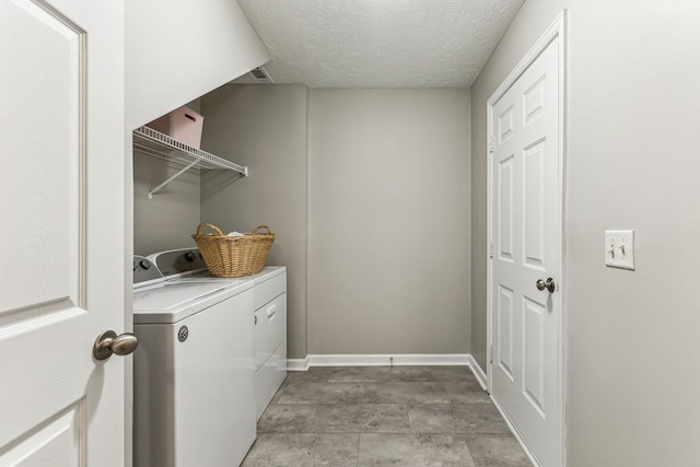 washroom featuring laundry area, baseboards, washer and clothes dryer, and a textured ceiling