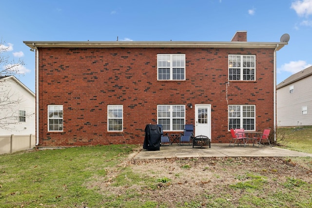 rear view of house with brick siding, a chimney, a lawn, a patio area, and fence