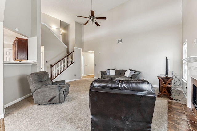 living area featuring a fireplace with flush hearth, visible vents, stairway, and baseboards