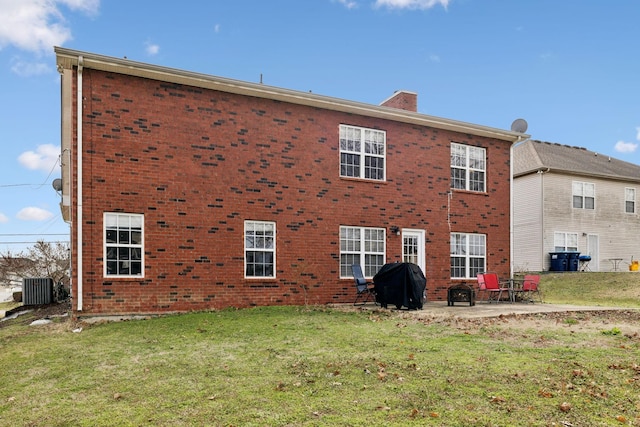 rear view of property with a patio, a chimney, a yard, central air condition unit, and brick siding