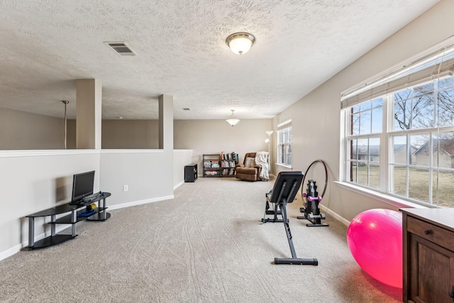 workout area featuring carpet floors, visible vents, a textured ceiling, and baseboards