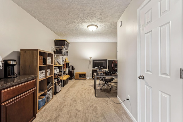 home office with light carpet, a textured ceiling, and baseboards