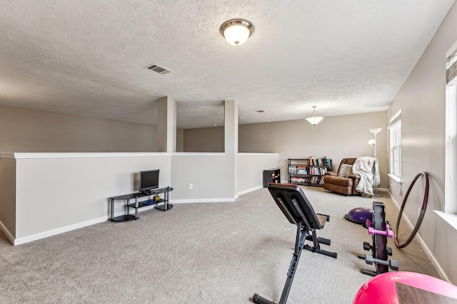 exercise room with a textured ceiling, carpet flooring, visible vents, and baseboards