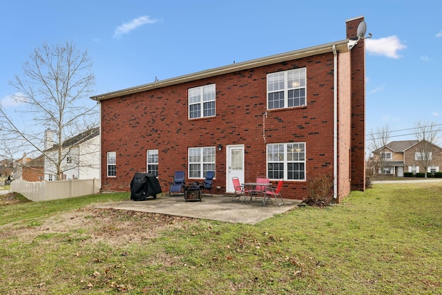 back of house featuring a patio area, a chimney, brick siding, and a yard