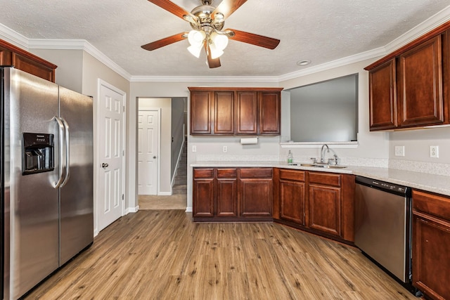 kitchen with stainless steel appliances, a textured ceiling, light countertops, light wood-type flooring, and a sink