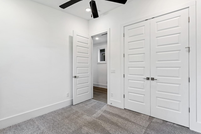 unfurnished bedroom with a closet, carpet, a ceiling fan, and baseboards