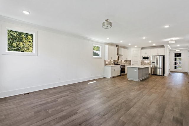 kitchen with open floor plan, stainless steel appliances, a kitchen island, and light countertops