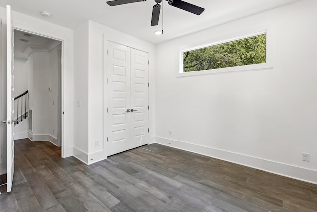 unfurnished bedroom with ceiling fan, dark wood-style flooring, a closet, and baseboards