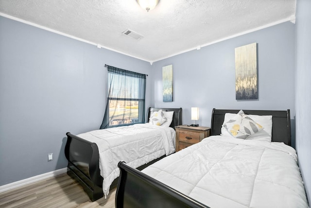 bedroom featuring a textured ceiling, visible vents, baseboards, light wood-type flooring, and crown molding