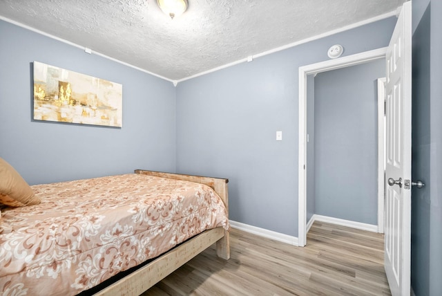 bedroom with light wood-type flooring, a textured ceiling, and baseboards