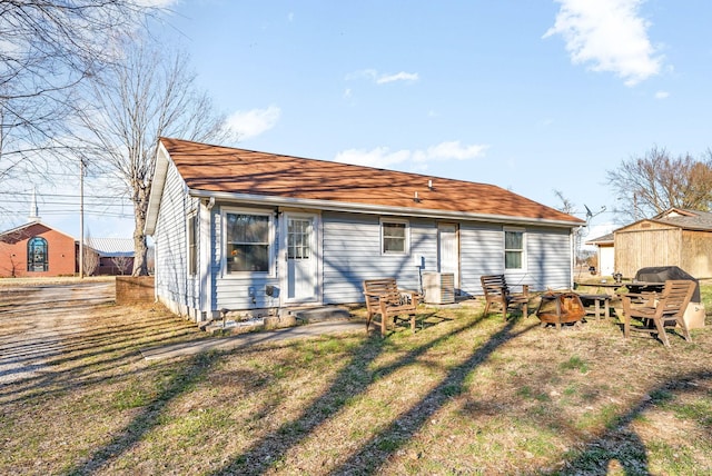 rear view of property with entry steps, central AC, and a yard