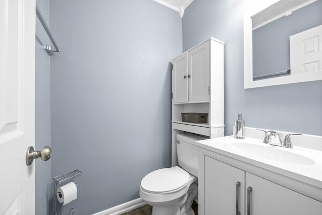 half bathroom with baseboards, vanity, and toilet