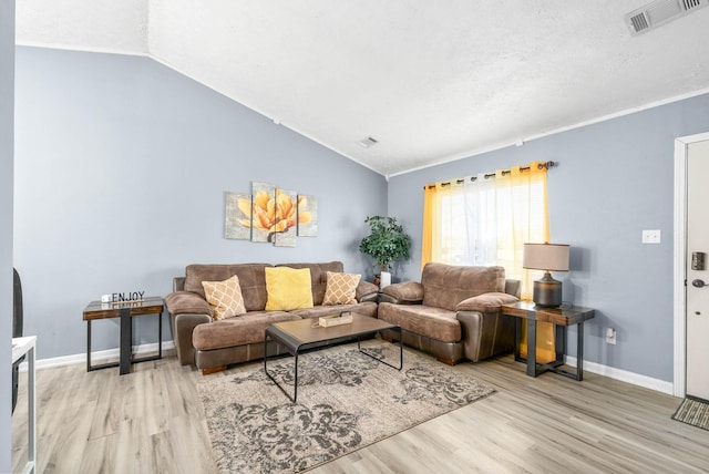 living room with light wood finished floors, baseboards, visible vents, and vaulted ceiling