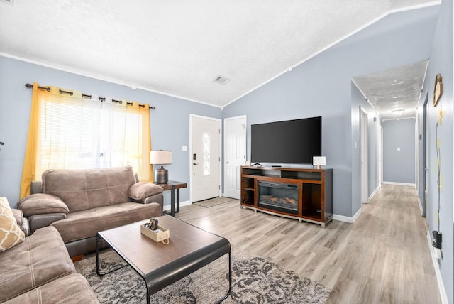 living area featuring light wood-style floors, lofted ceiling, visible vents, and baseboards