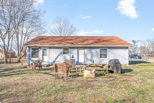 back of property featuring entry steps and a lawn