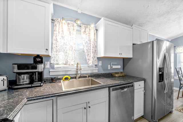 kitchen featuring stainless steel appliances, plenty of natural light, a sink, and white cabinets