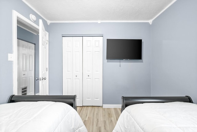 bedroom featuring light wood-style floors, a textured ceiling, baseboards, and a closet