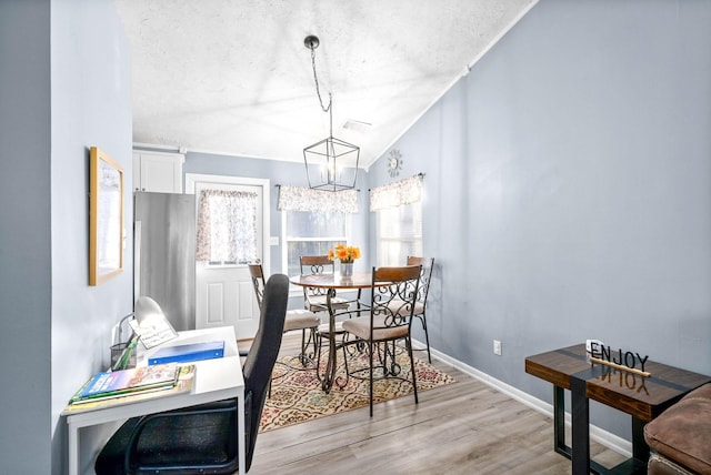 dining space featuring baseboards, vaulted ceiling, a textured ceiling, light wood-type flooring, and a chandelier