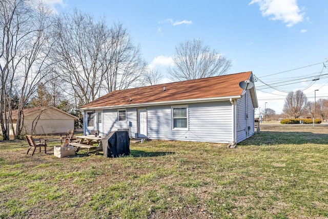 back of property with an outdoor fire pit and a lawn