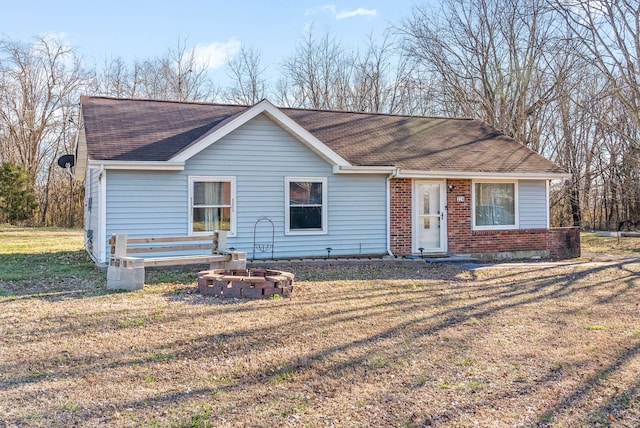 ranch-style home with a shingled roof, a front yard, and brick siding