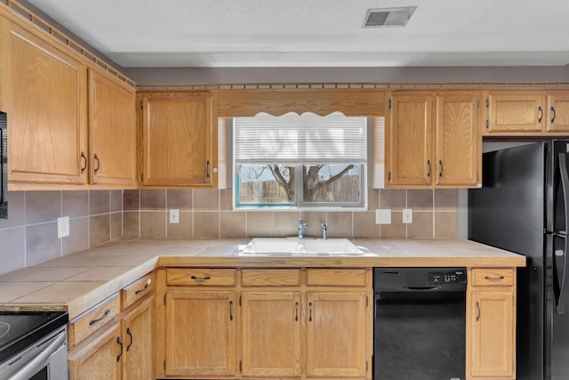 kitchen with tile countertops, a sink, visible vents, backsplash, and black appliances