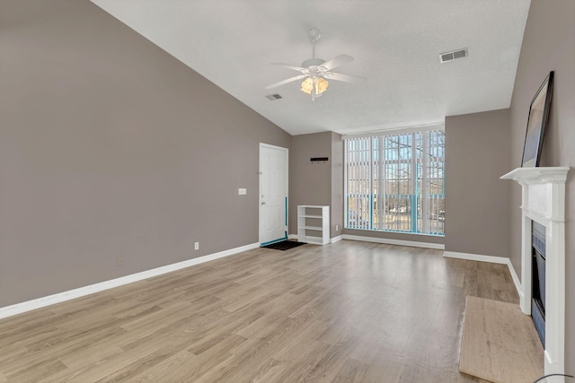 unfurnished living room with a fireplace, a ceiling fan, visible vents, baseboards, and light wood finished floors