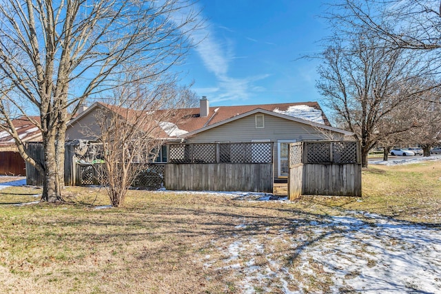 rear view of property with a yard, fence, a chimney, and a carport