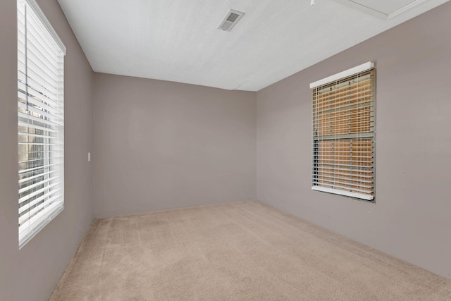 carpeted empty room with visible vents and a textured ceiling