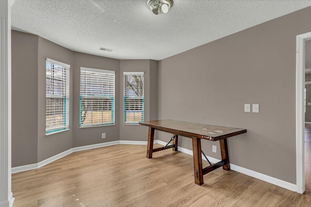 office area featuring a textured ceiling, visible vents, light wood-style flooring, and baseboards