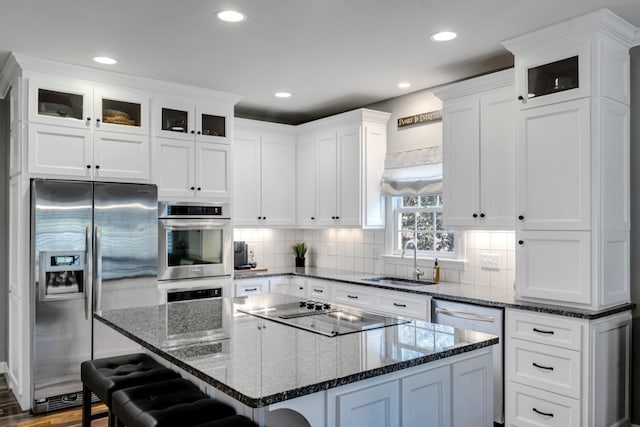 kitchen featuring a kitchen bar, a kitchen island, appliances with stainless steel finishes, and a sink