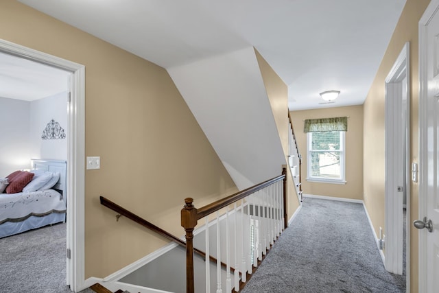 corridor featuring baseboards, light colored carpet, and an upstairs landing