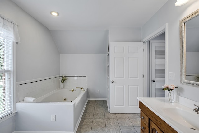 full bathroom featuring lofted ceiling, baseboards, vanity, and a whirlpool tub