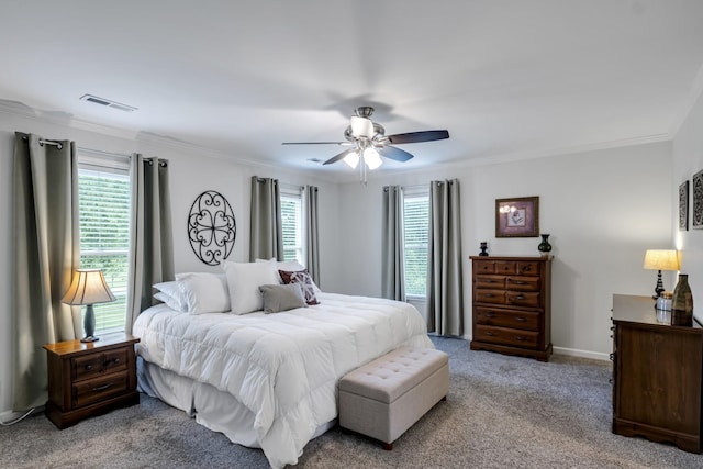 carpeted bedroom with ornamental molding, a ceiling fan, visible vents, and multiple windows