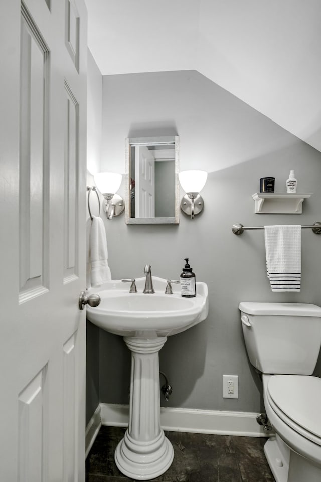 bathroom featuring lofted ceiling, toilet, and baseboards