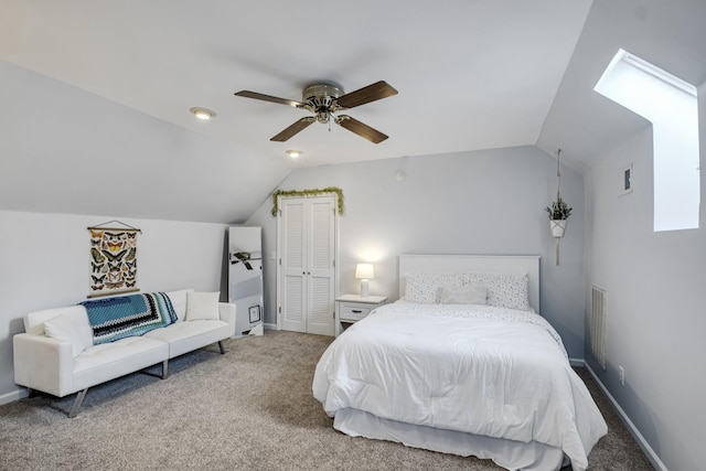 carpeted bedroom with a ceiling fan, lofted ceiling with skylight, visible vents, and baseboards