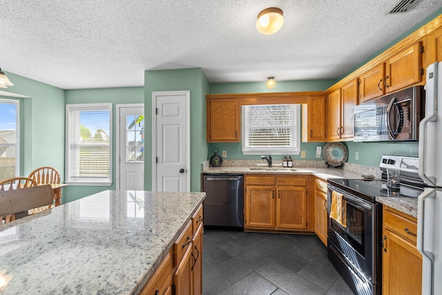 kitchen featuring stainless steel appliances, brown cabinetry, and a sink