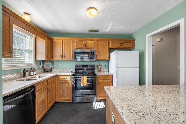 kitchen featuring light stone counters, appliances with stainless steel finishes, a sink, and visible vents