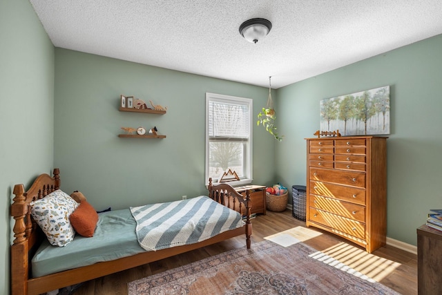 bedroom with a textured ceiling, wood finished floors, and baseboards