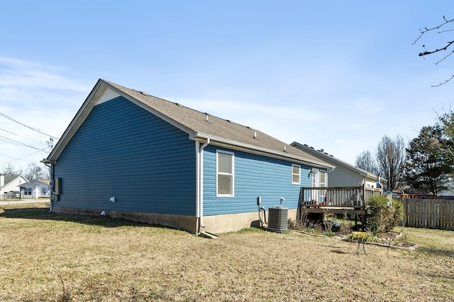 back of property featuring fence, a lawn, a deck, and central AC unit