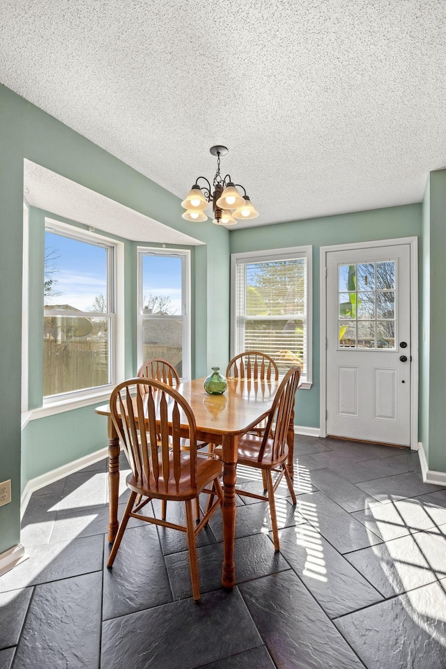 dining room featuring a chandelier, plenty of natural light, and baseboards