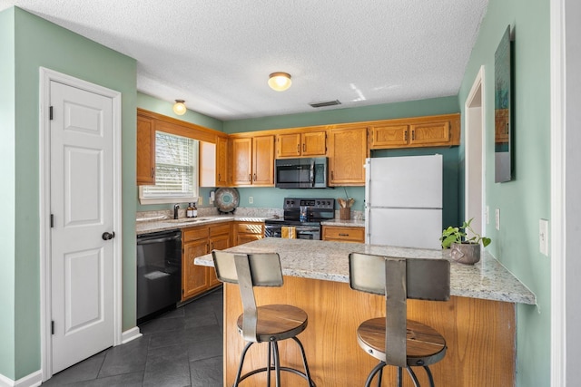 kitchen featuring black dishwasher, freestanding refrigerator, a peninsula, stainless steel electric stove, and a sink